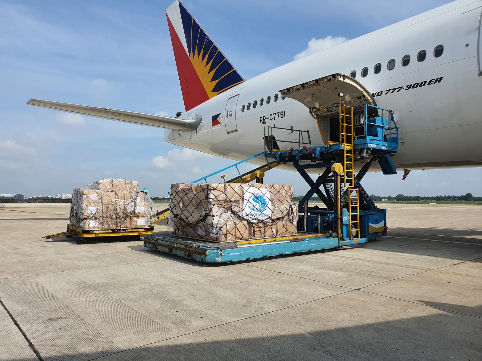 Air cargo pallets on a loader beside an aircraft